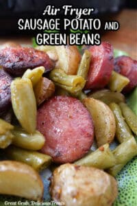 A green plate with sliced smoked sausage, potatoes, and green beans with the title of the recipe in text at the top.