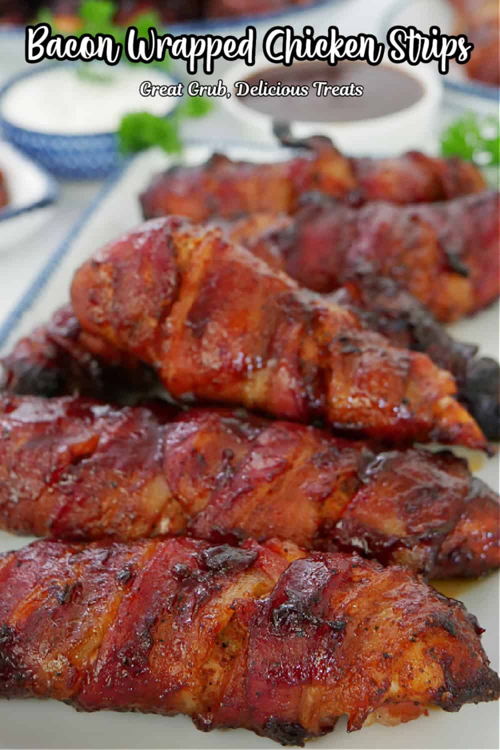 A white rectangle plate with blue trim with six smoked bacon wrapped chicken strips on it and the title of the recipe at the top.