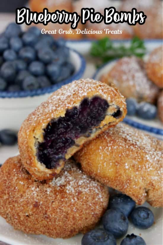 A white plate with three fried blueberry pie bombs with a bite taken out of the one on top with the title of the recipe at the top.