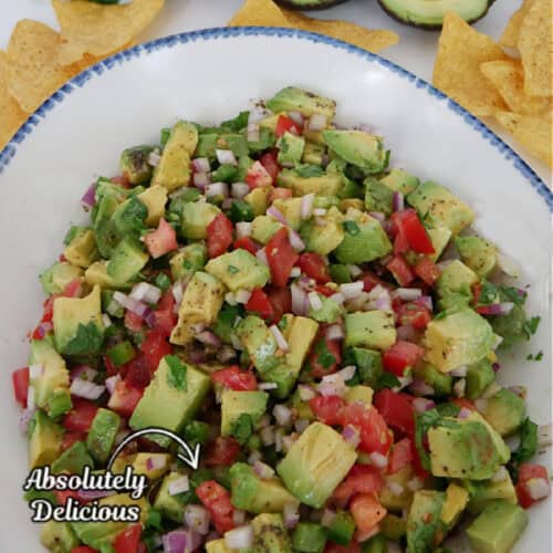 A white bowl with blue trim filled with a chunky avocado salsa with the title in text at the top of the photo.