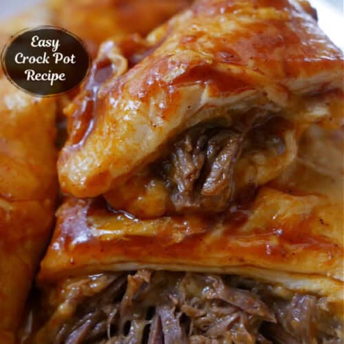 A close up photo of beef enchiladas on a white plate showing the beef and cheese inside the tortillas.