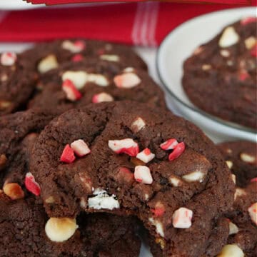 Chocolate peppermint cookies on a counter with a bite taken out of the cookie in front.