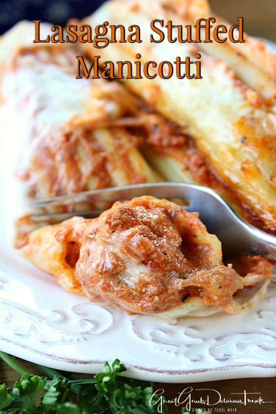 A white plate with two stuffed manicotti on it and a fork cutting a bite off one of the manicottis. 