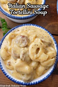 Two white bowls with blue trim filled with a serving of Italian sausage tortellini soup.