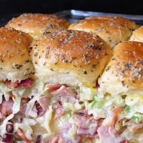 A baking dish with six Italian sliders in it.