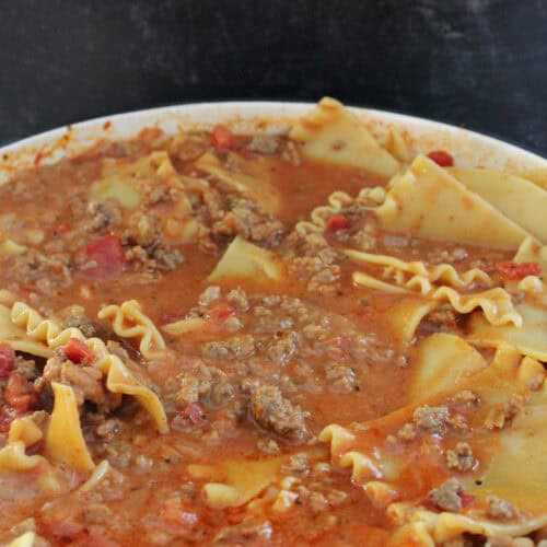 A white cast iron pot with homemade lasagna soup in it.