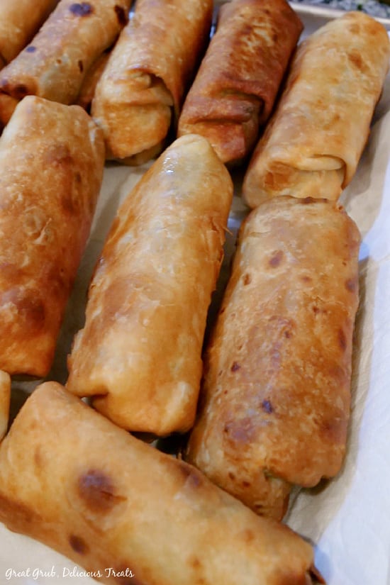 Fried Burritos are crispy and crunchy, full of beef, ground beef and pork, two types of cheese and more. A baking sheet lined with paper towels with 8 fried burritos on it.