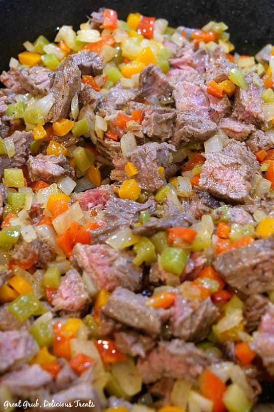 Beef flank steak with three different bell peppers and onions, seasoned deliciously and cooked until tender in a pan.