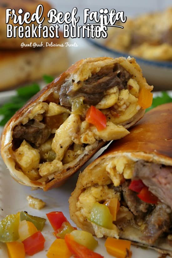 A beef fajita breakfast burrito cut in half, placed on a white plate, showing the ingredients.