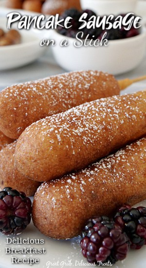 Pancake Sausage on a Stick are delicious sausage links dipped in a homemade maple pancake mix and fried to a perfect golden brown outside. A close up photo of pancake sausage on a stick stacked on top of each other on a white plate with blackberries in the foreground.