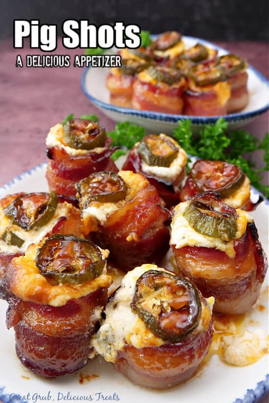 A white plate with blue trim with eight pig shot appetizers on it.