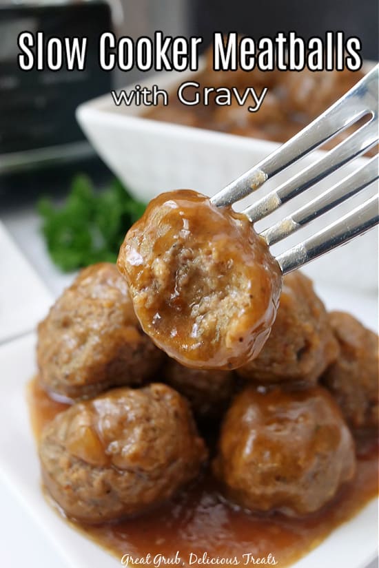 A meatball on a fork with a bite taken out of it, over a pile of meatballs on a white plate.
