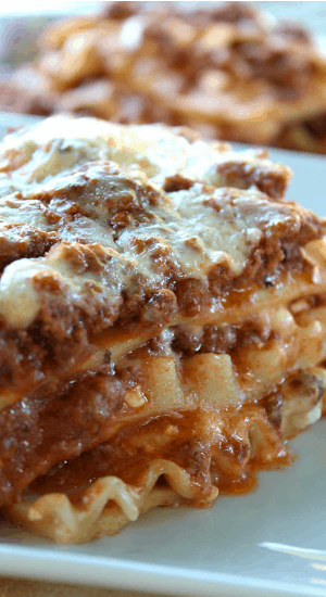 This Classic Lasagna is loaded with cheese, is an easy meat lasagna recipe and a delicious go-to lasagna recipe the whole family will absolutely love. A serving of Lasagna on a white plate.